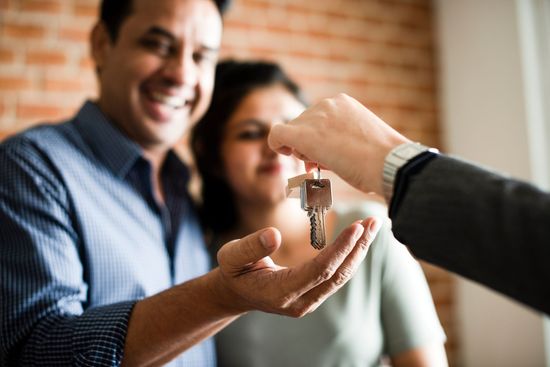 Couple receiving house keys from agent after successful home purchase.