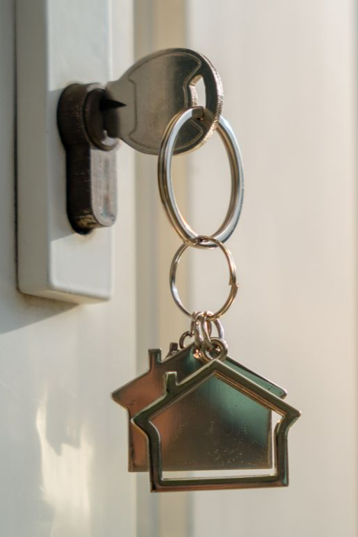 House key hanging in front door lock, symbolizing sell process and buy my house fast solution.
