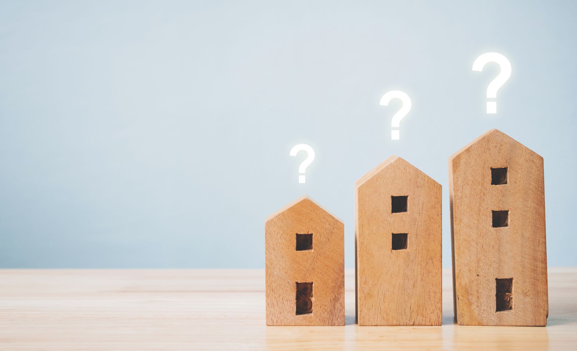 Picture of three wooden homes with a question mark on top.