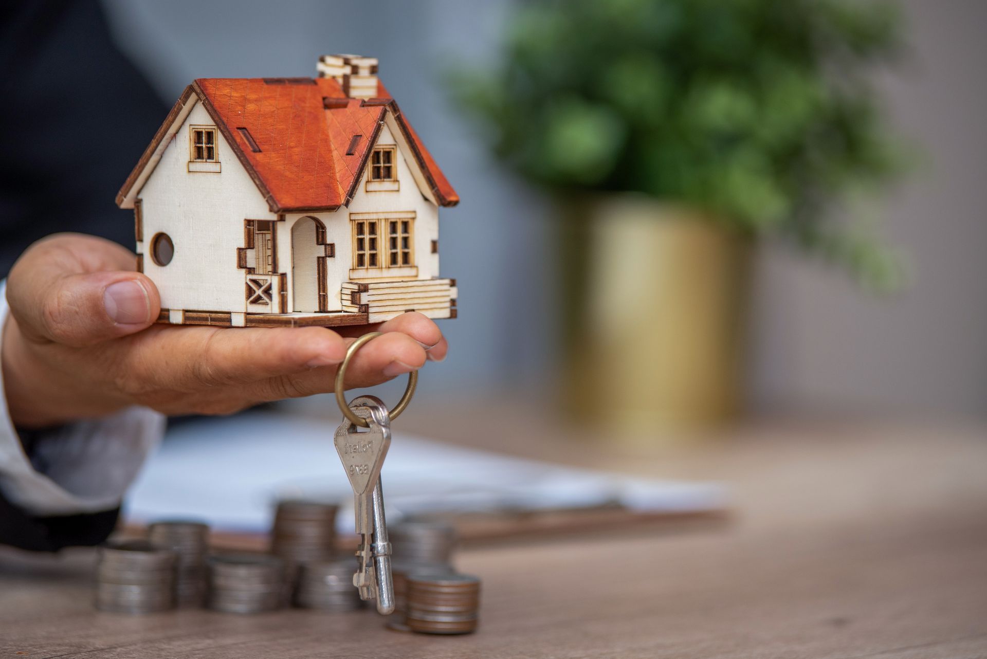 A man in St. Paul, MN, holds a house key and coins on a table, representing Cash Home Buyers.