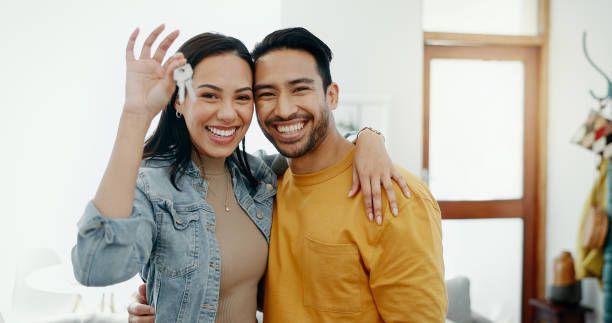 Happy fast-closing homebuyer couple holding house keys and smiling after a quick home purchase.