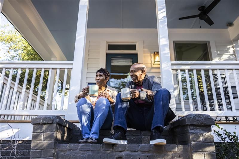 Senior couple having coffee on front porch.