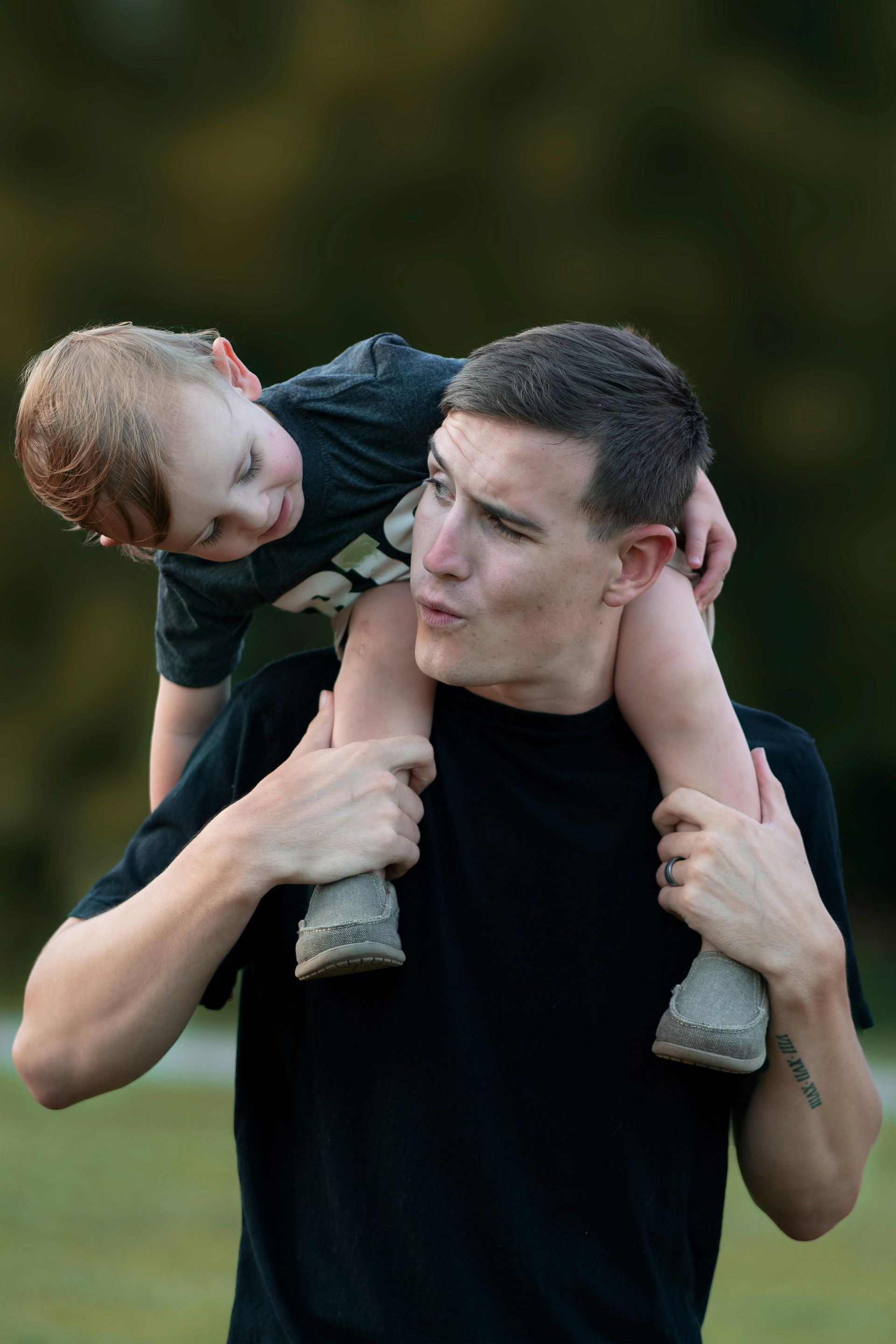 Man carrying a child on his shoulders outdoors.