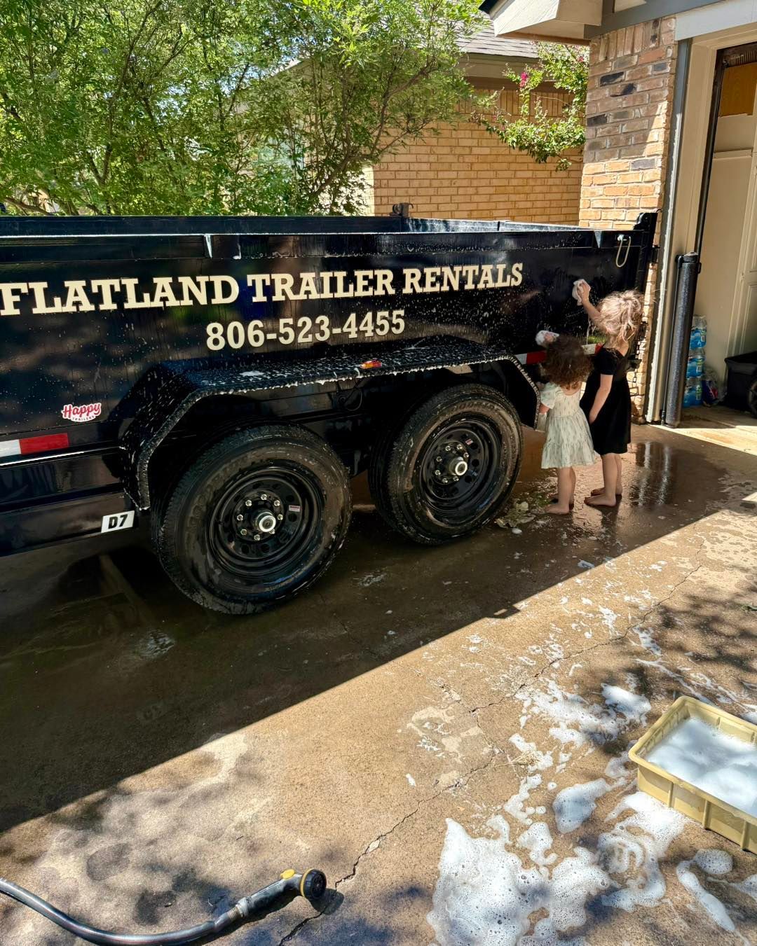 Children washing a black trailer with the words 