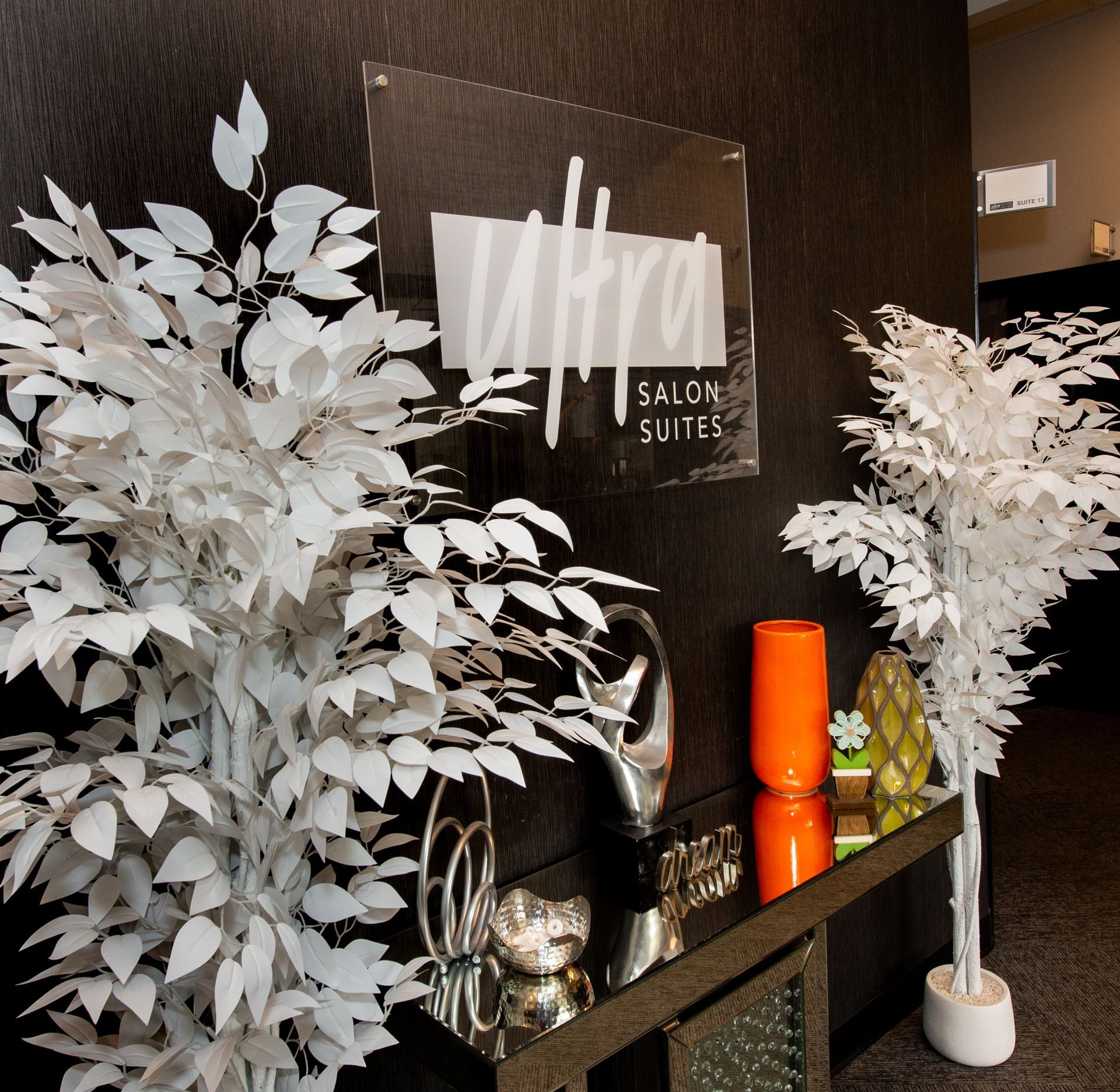 A sign for ultra salon suites hangs on a wall