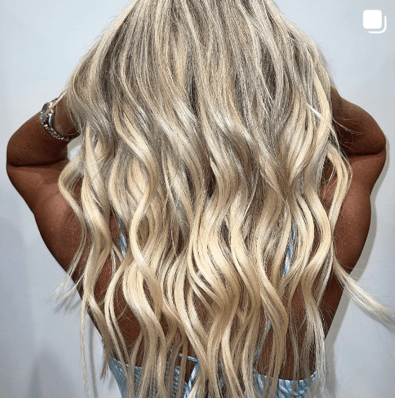 The back of a woman with long blonde wavy hair.