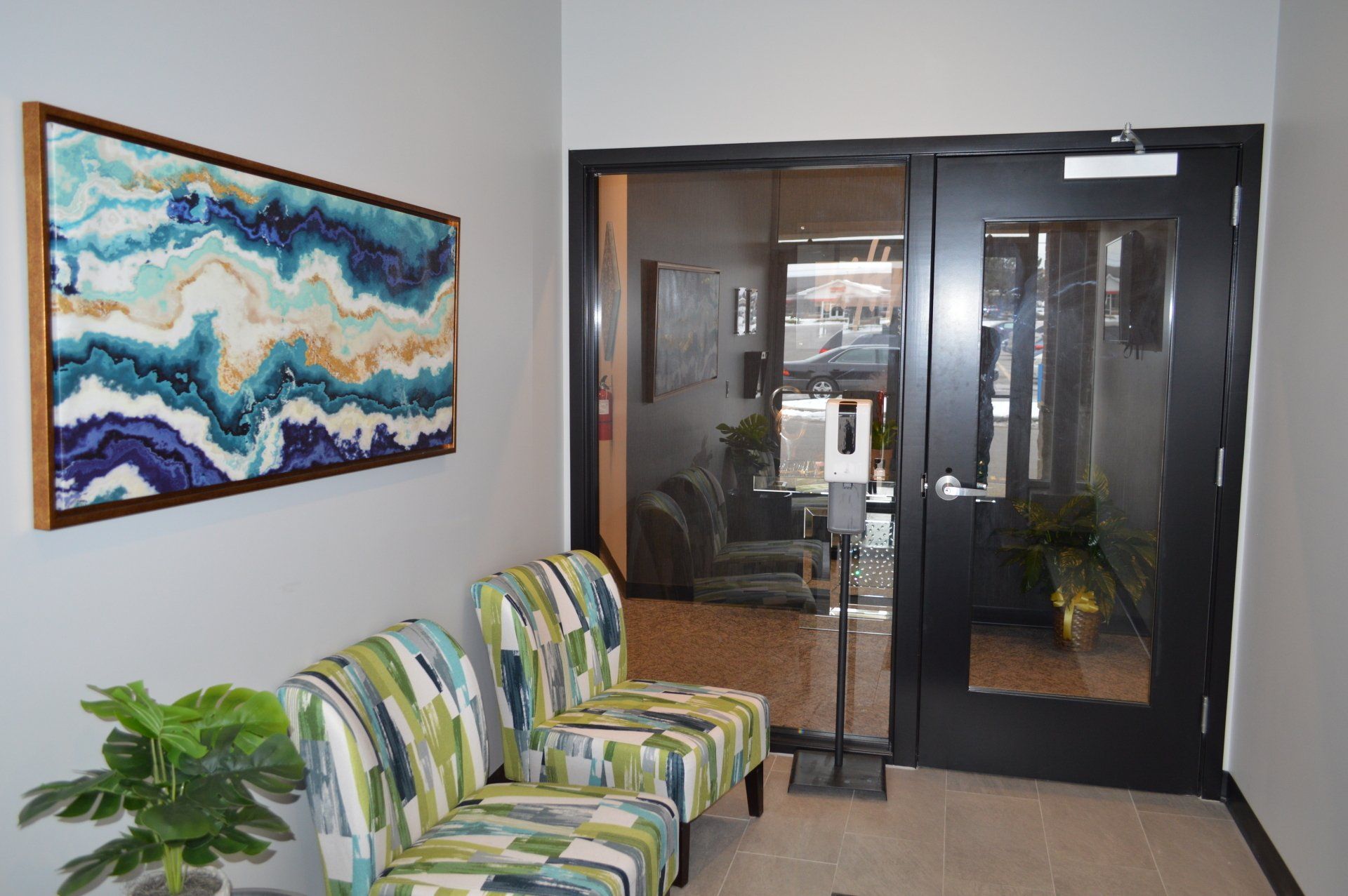 A waiting room with chairs and a painting on the wall.