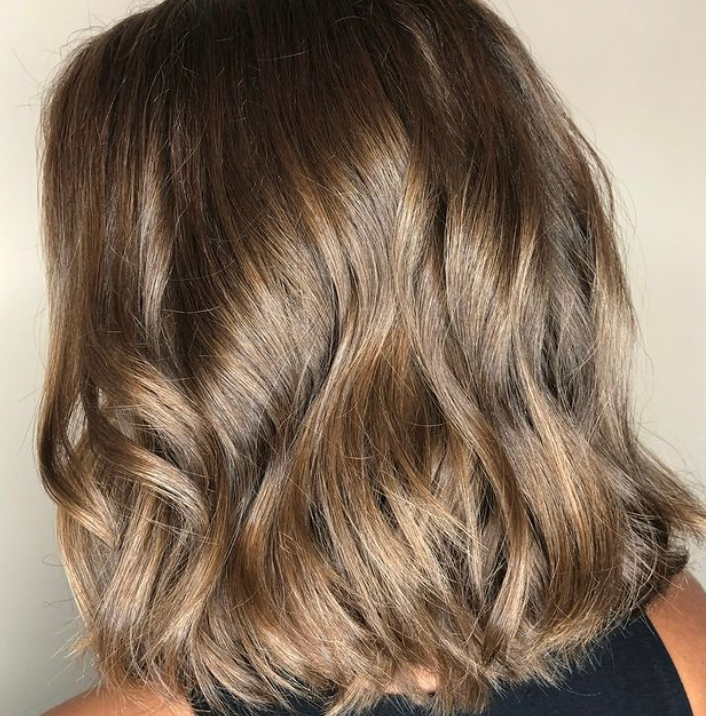 A woman with short brown hair is wearing a black tank top.