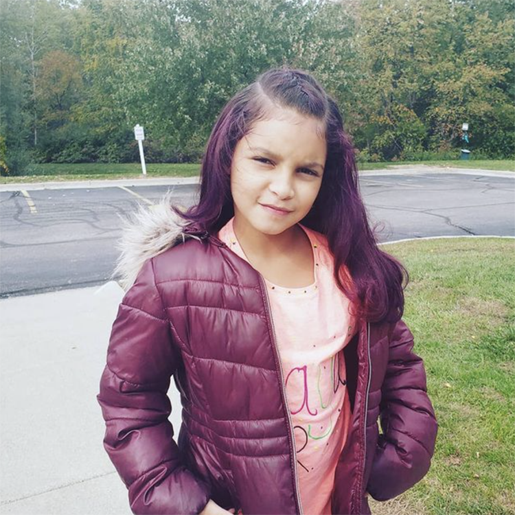 A little girl with purple hair wearing a purple jacket