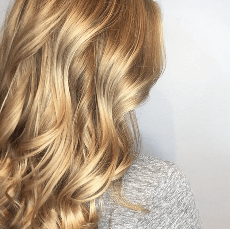 A woman with long blonde hair is wearing a grey shirt.