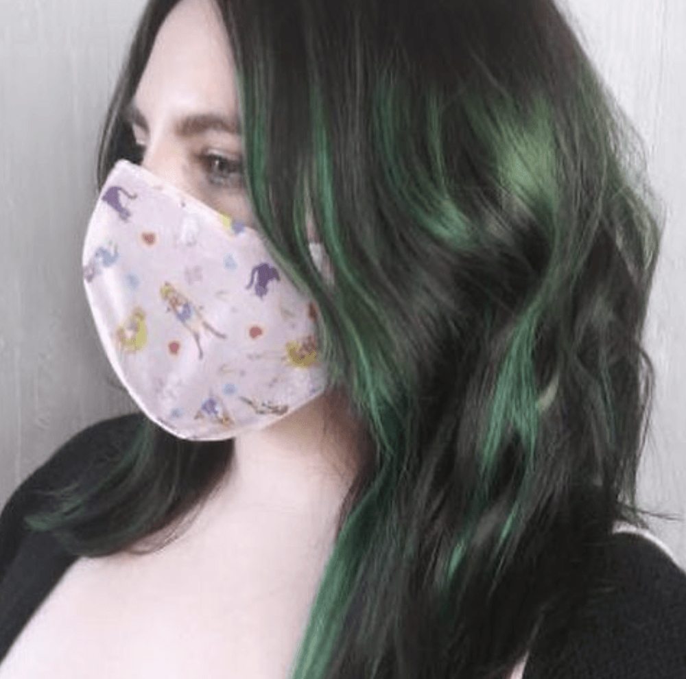 A woman with green hair is wearing a face mask.