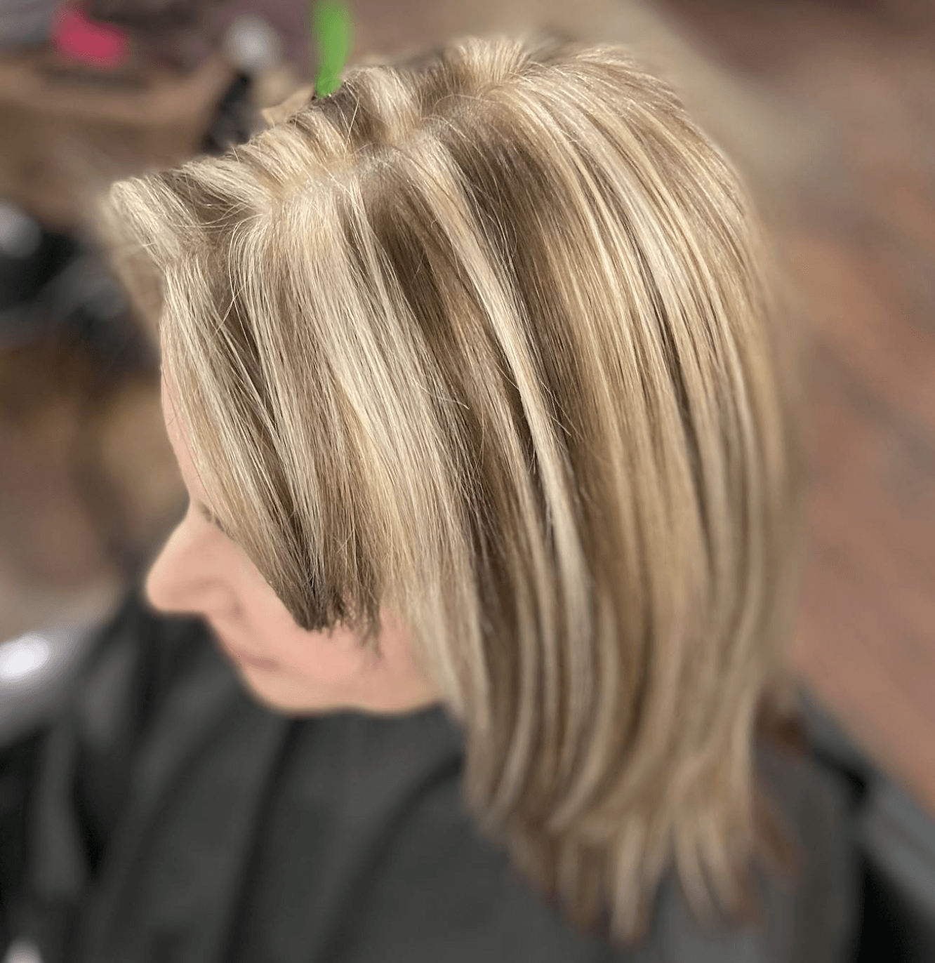 A woman with blonde hair is getting her hair cut by a hairdresser.