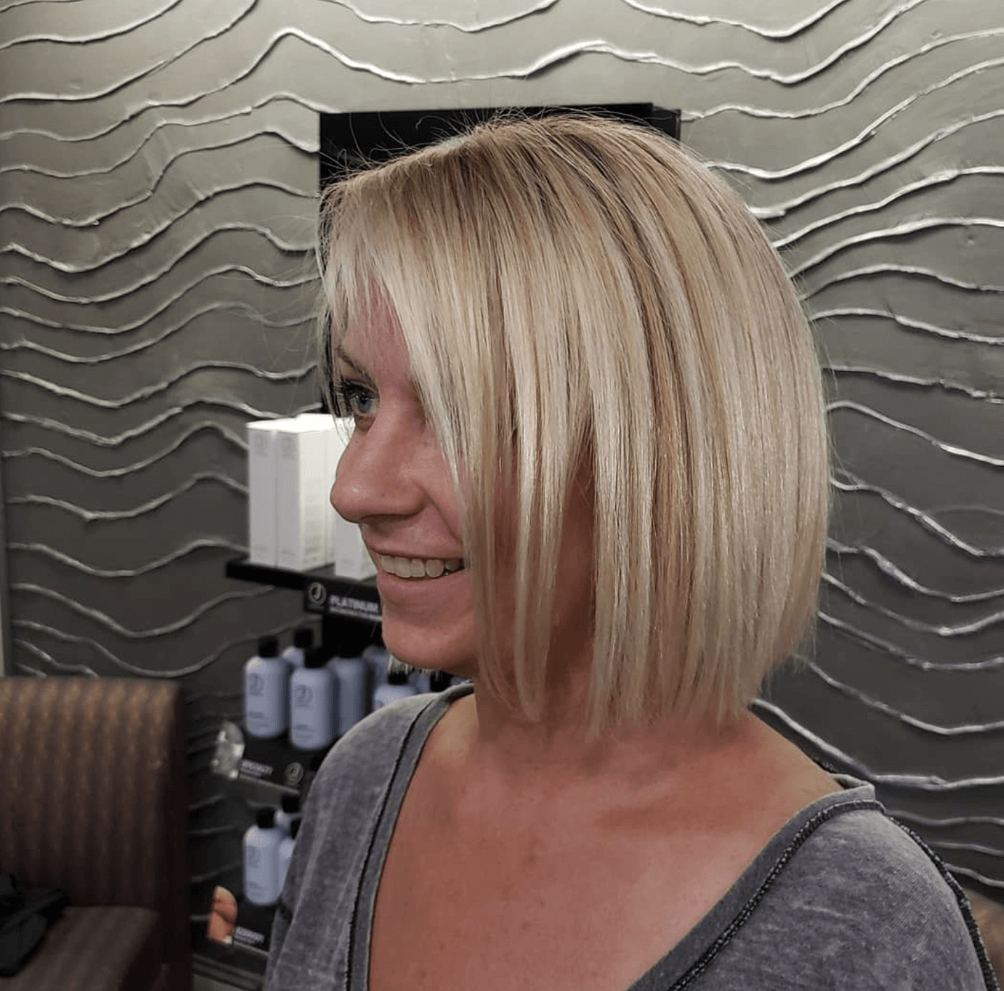 A woman with blonde hair is smiling in a salon