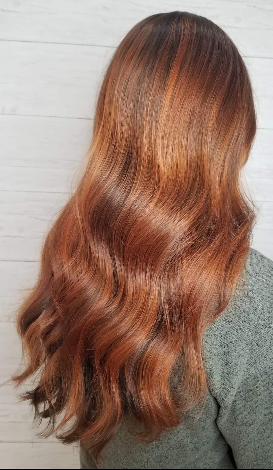 A woman with long red hair is wearing a green sweater.