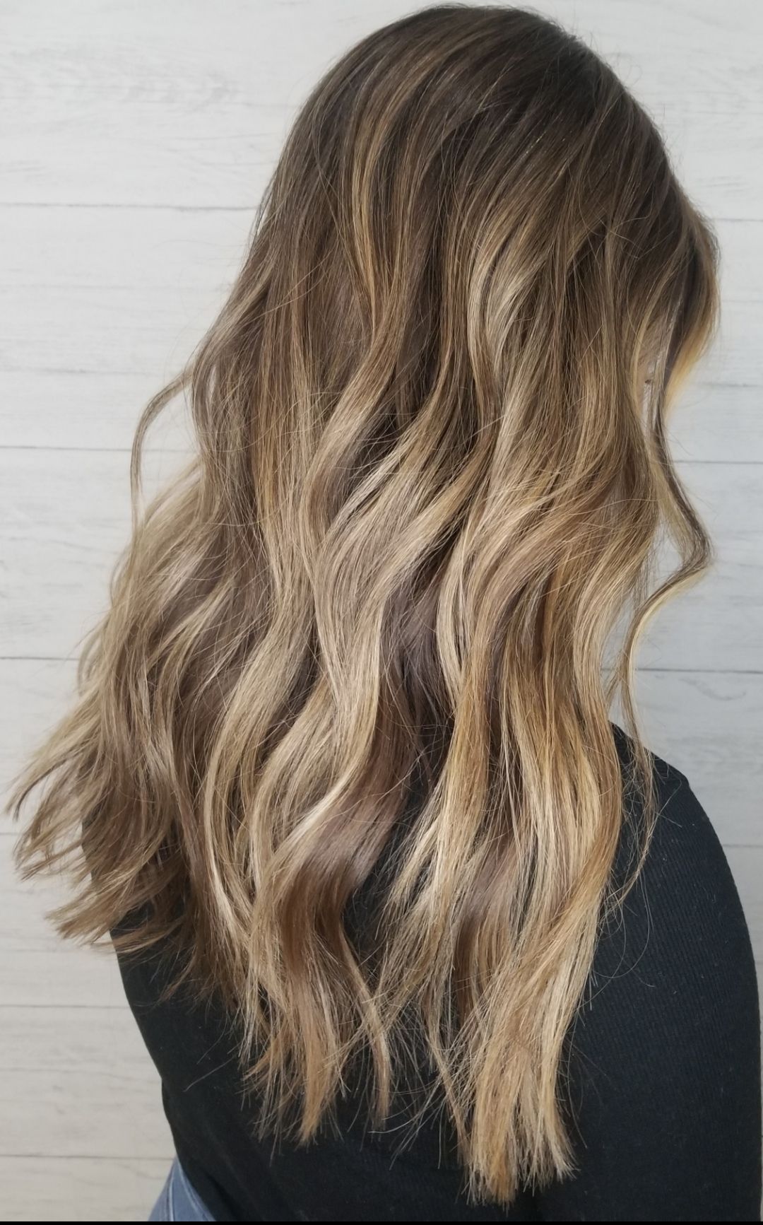 A woman with long wavy blonde hair is wearing a black shirt.