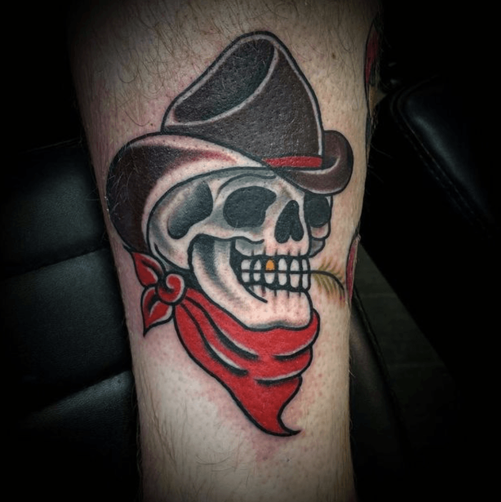 A tattoo of a skull wearing a cowboy hat and a red bandana.