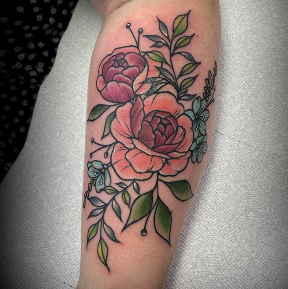 A woman has a tattoo of flowers and leaves on her forearm