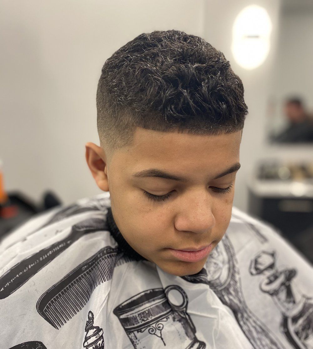 A young boy is getting his hair cut at a barber shop.