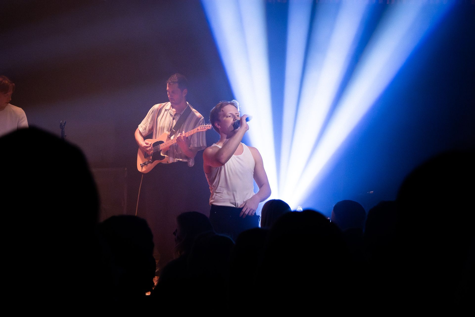 Króli performing live in Berg hall at Hljómahöll, with dramatic stage lighting and crowd silhouettes in the foreground.