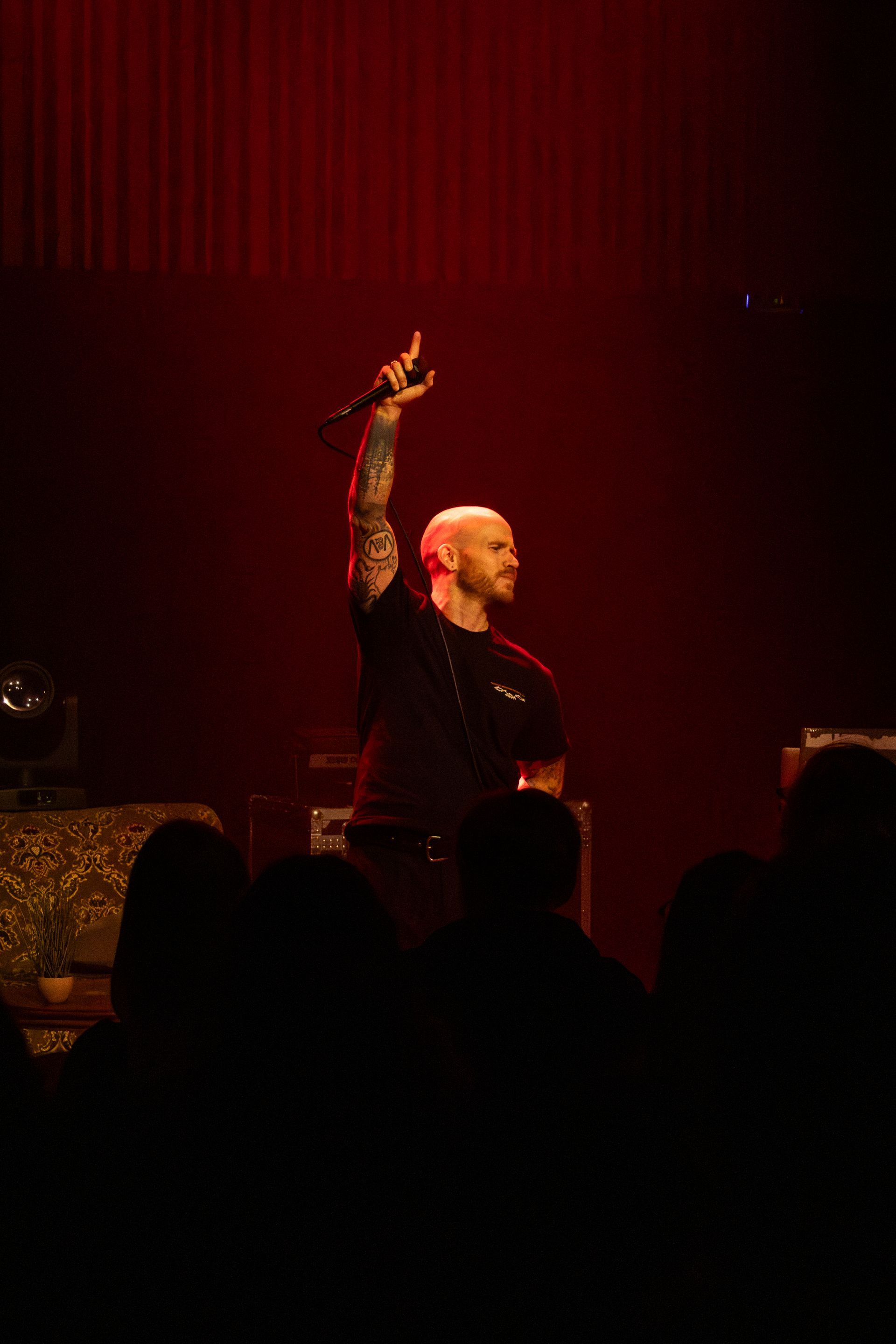 Emmsjé Gauti performing live in Berg at Hljómahöll, holding mic aloft under red stage lights.