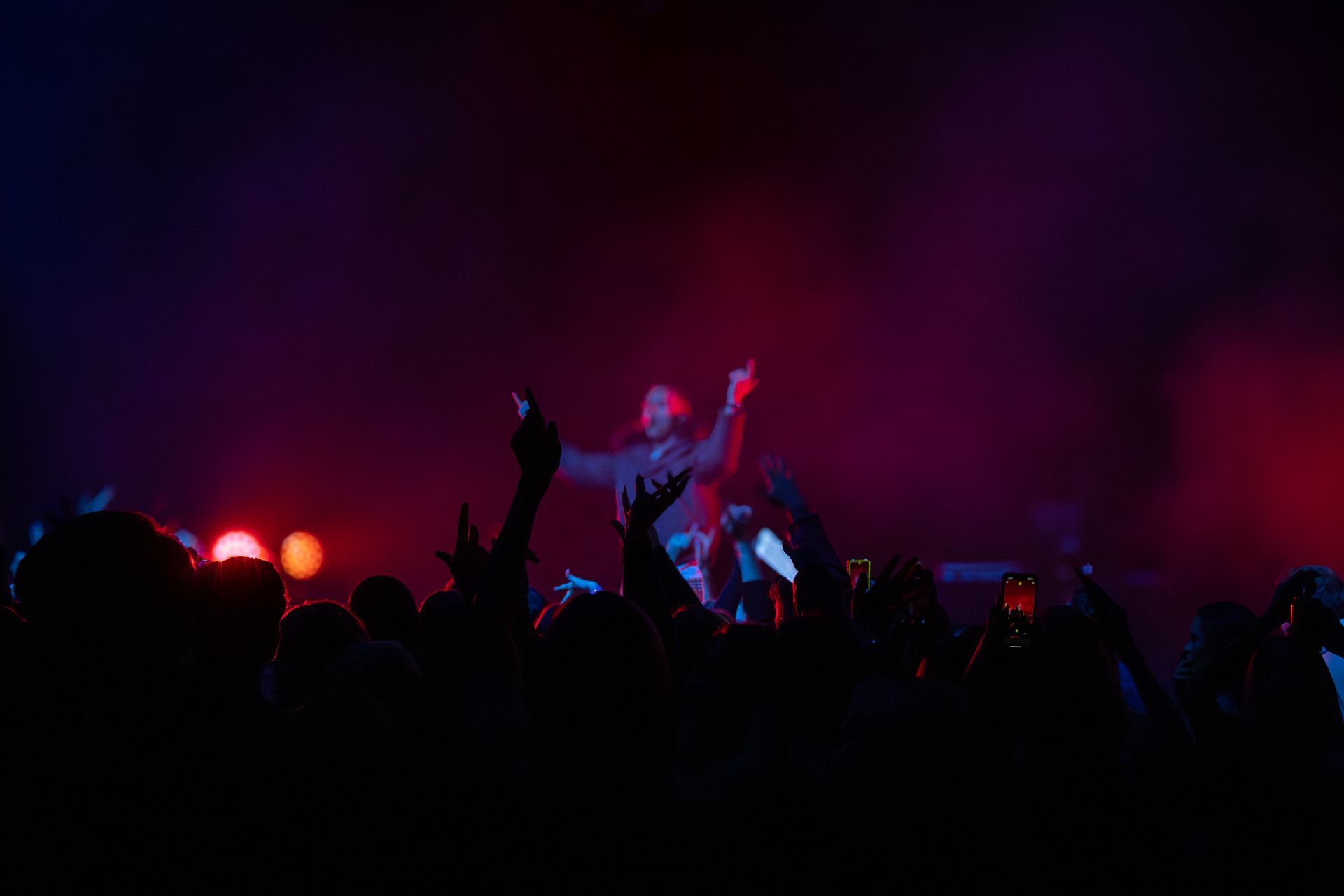 Crowd at Herra Hnetusmjör concert in Stapi at Hljómahöll, Keflavík, under red stage lights.