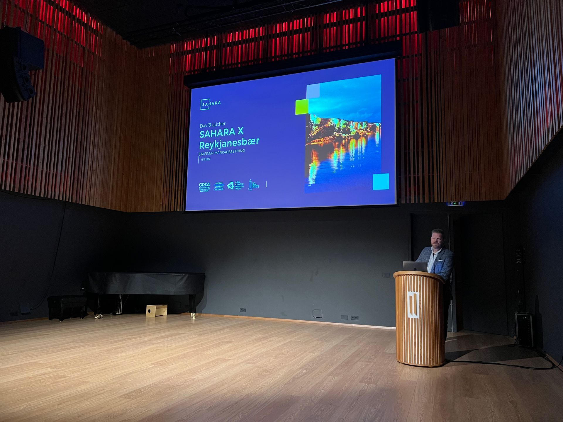 A speaker at a podium presents slides for