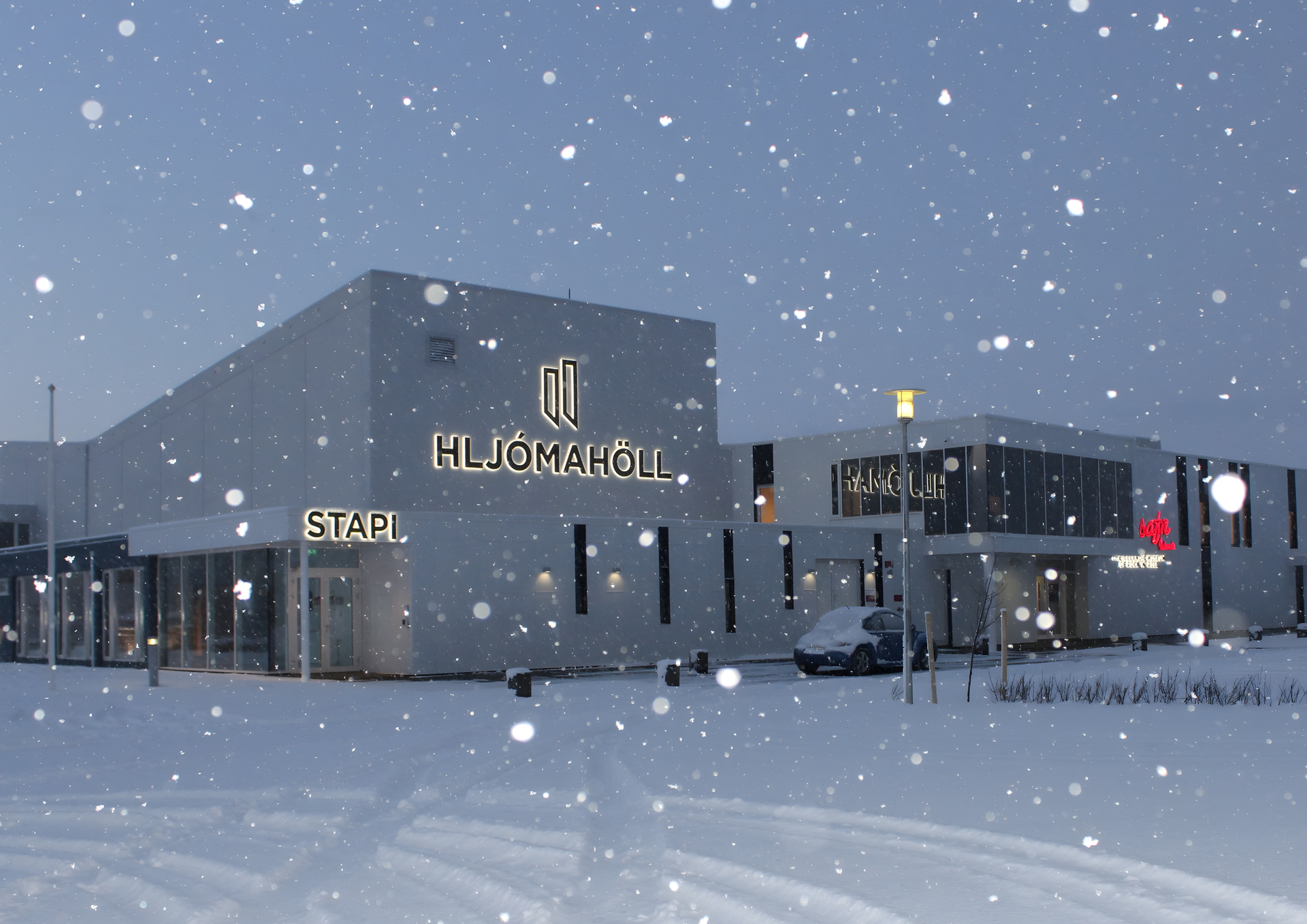 Hljómahöll and Stapi in winter snow, illuminated exterior of the venue in Reykjanesbær at dusk.