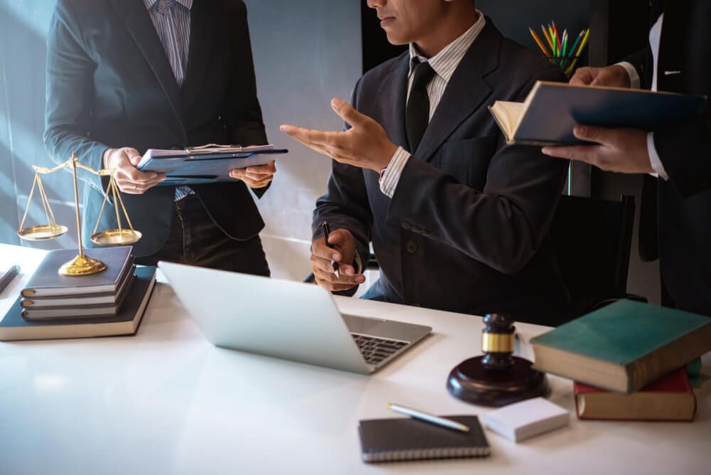 Legal Professional Engages in Conversation at Desk with Two Individuals — Lawyer in Wagga Wagga