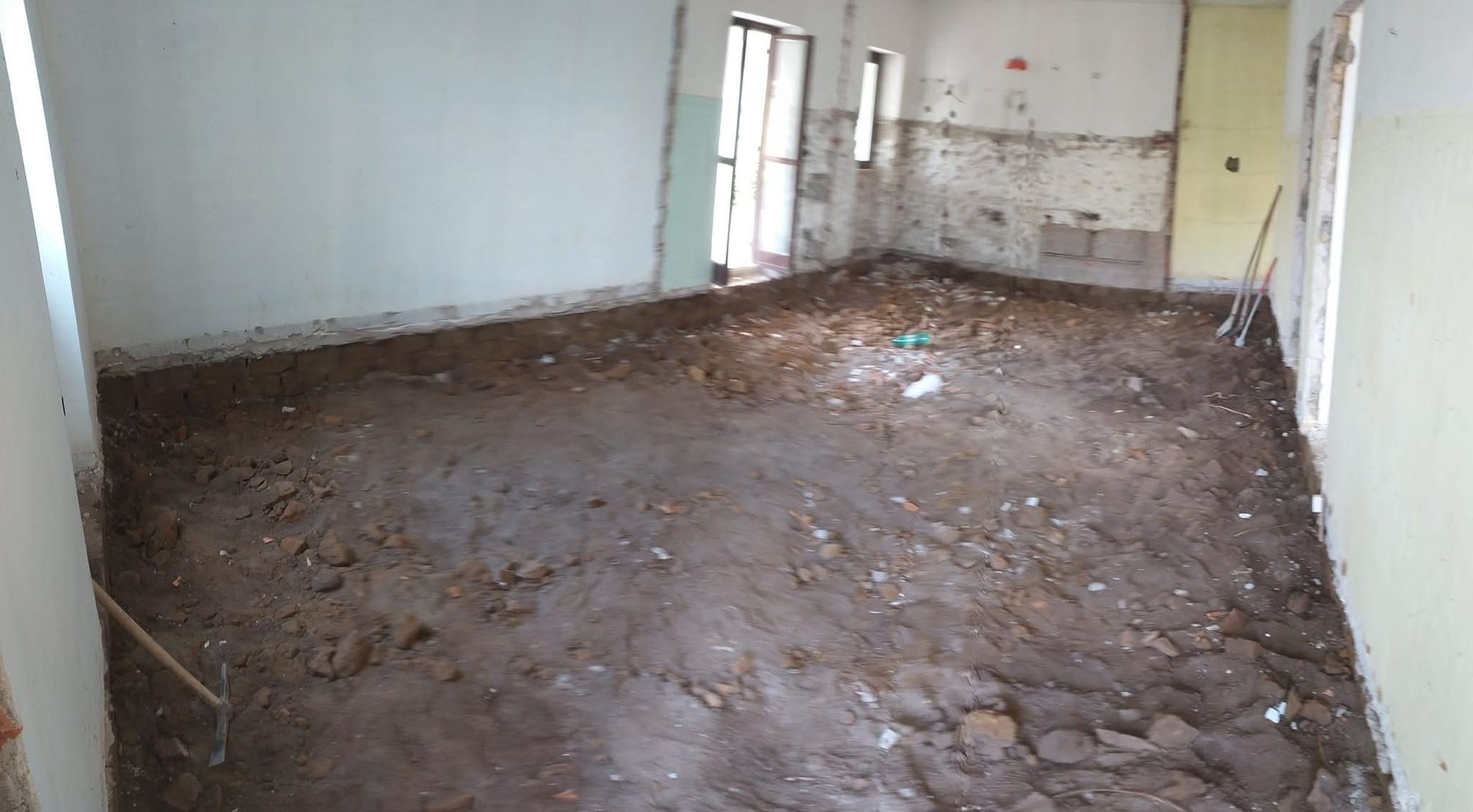Locale interno in costruzione, con pavimento in terra battuta e pareti parzialmente demolite.
