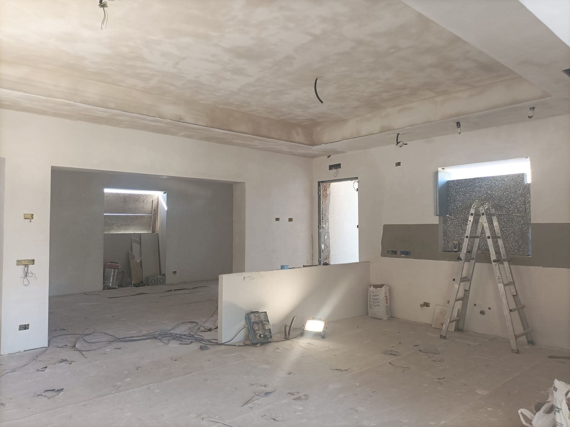 Interno di una stanza in costruzione, con pareti e soffitto esposti e detriti sul pavimento.