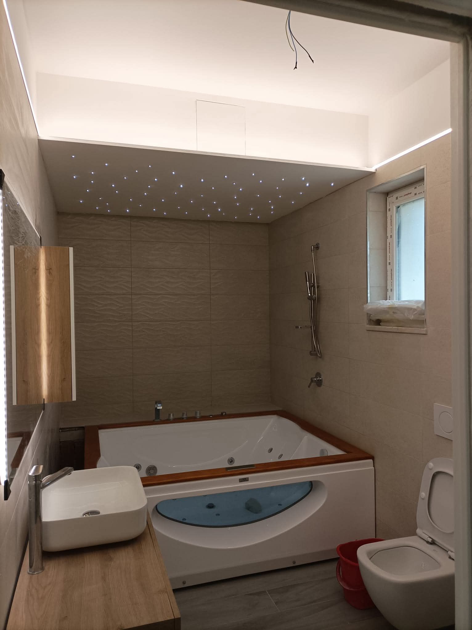 Bagno con vasca idromassaggio, WC e lavandino. Pareti beige, dettagli in legno e soffitto a volta.