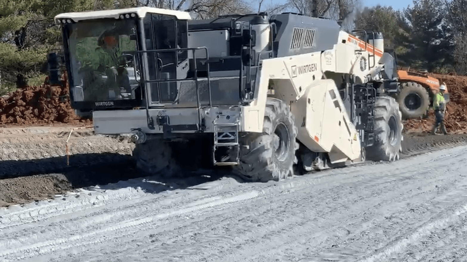 A large tractor is driving down a dirt road.