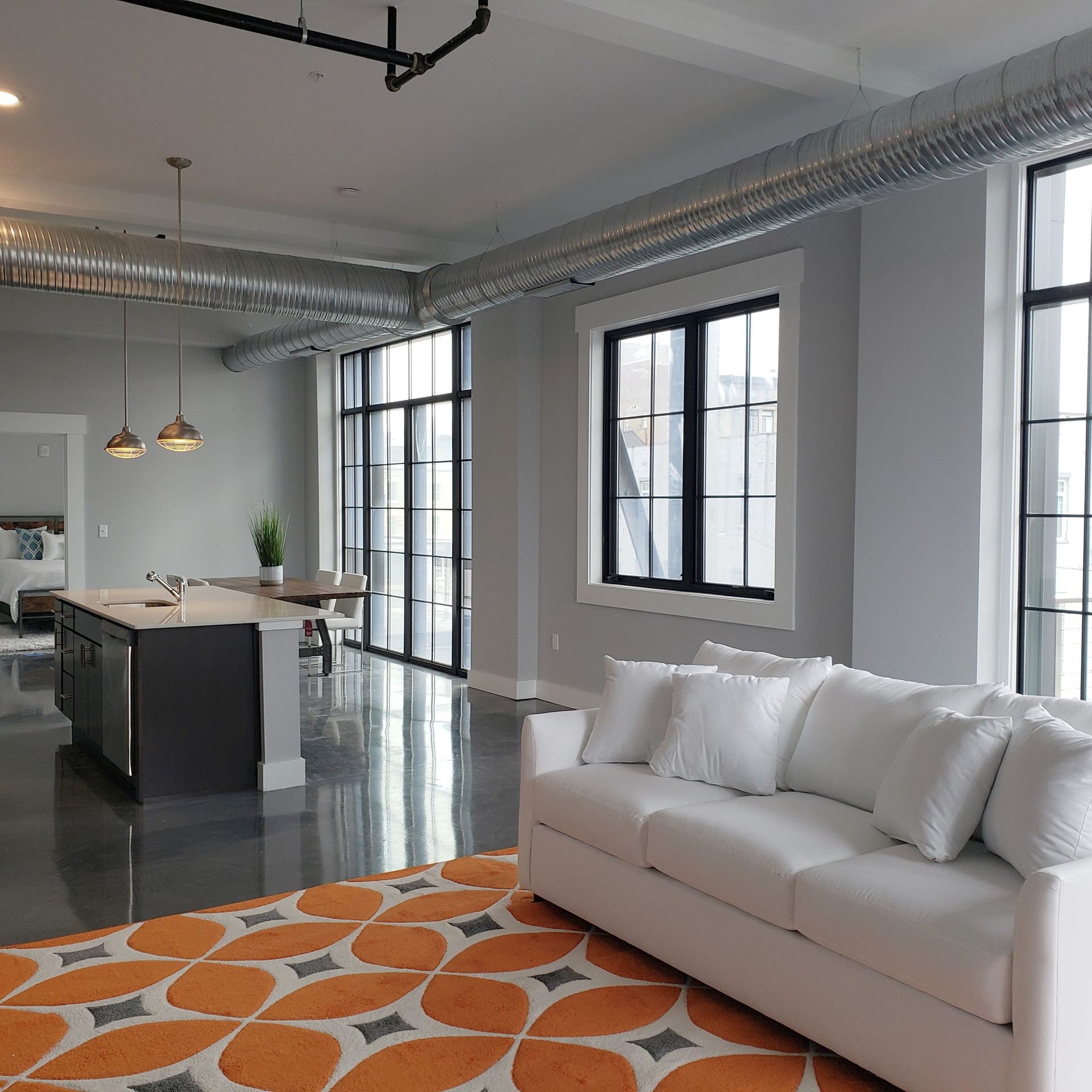 A living room with a white couch and an orange rug