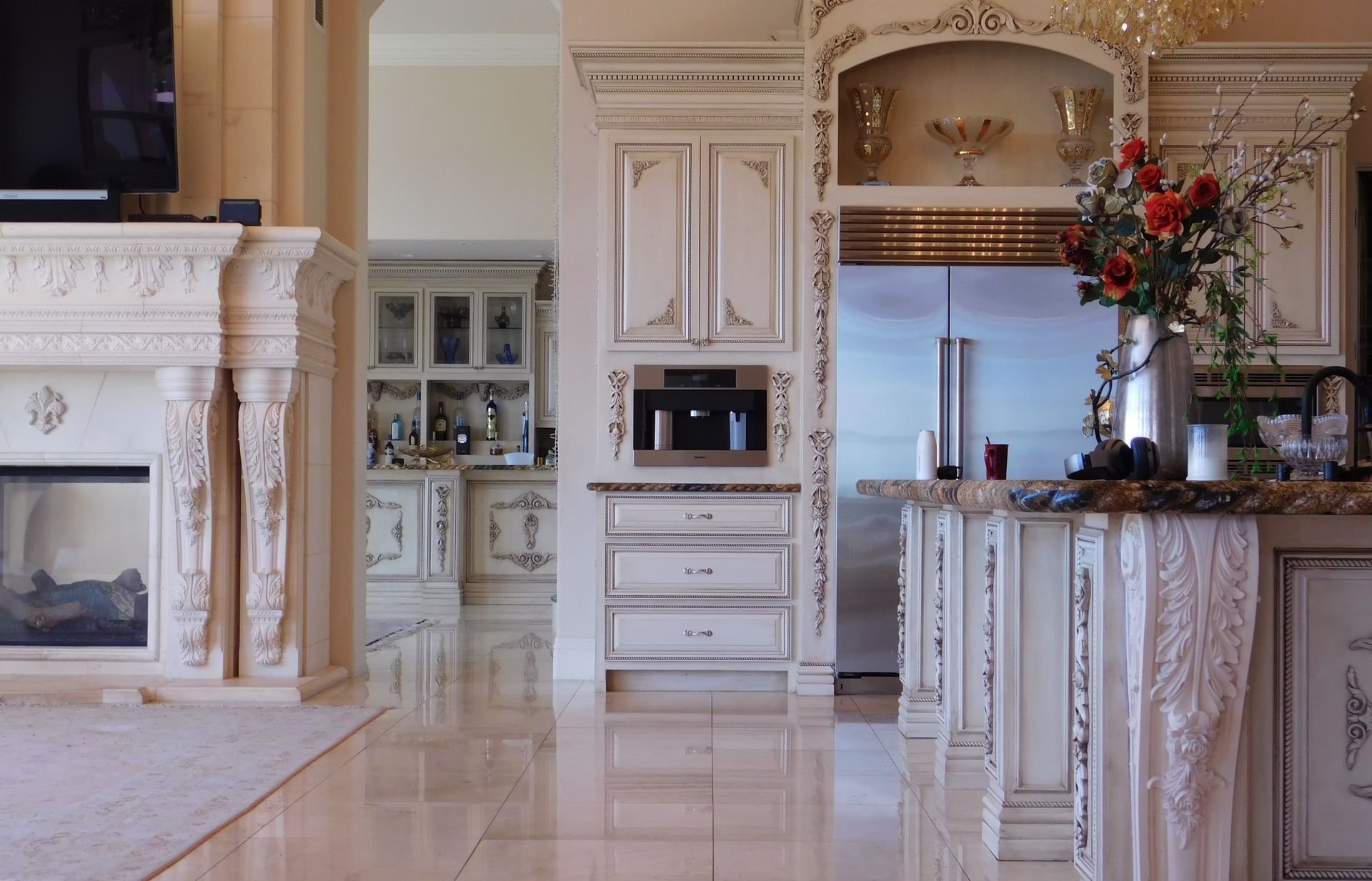 Ornate white kitchen and living space with marble floors and detailed cabinetry.