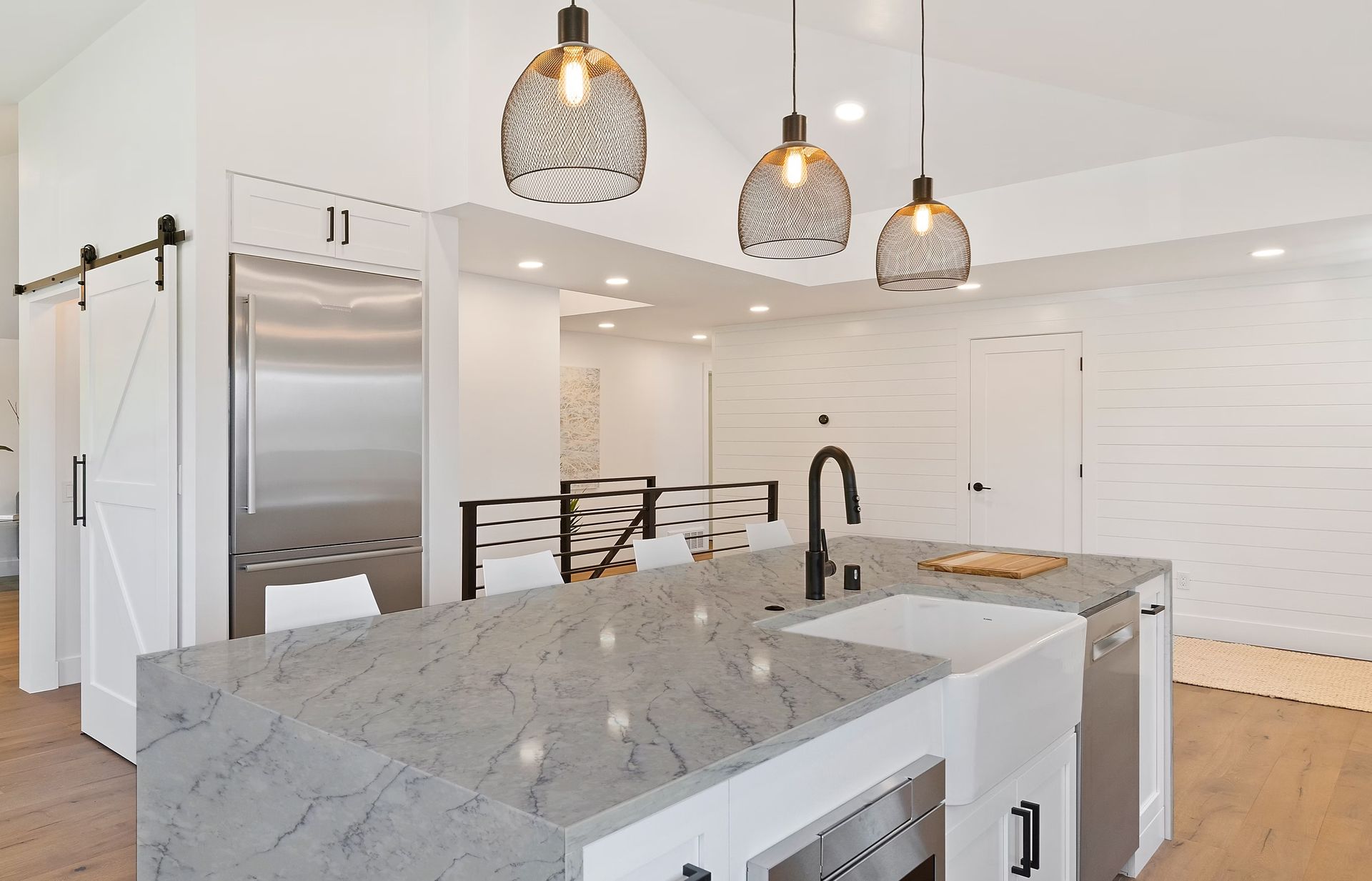 Modern kitchen with island, pendant lights, and stainless steel appliances.