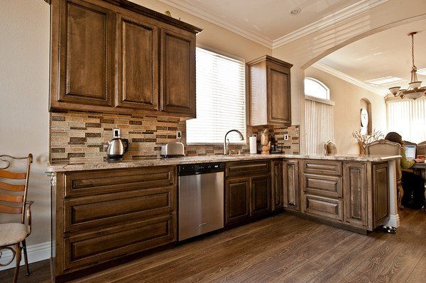Kitchen with dark wooden cabinets, stainless steel appliances, and tile backsplash.