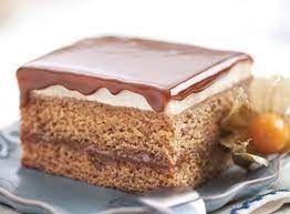 A piece of cake with chocolate frosting and whipped cream on a plate.