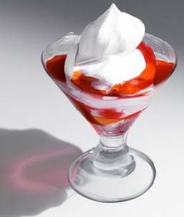 A martini glass filled with strawberries and whipped cream