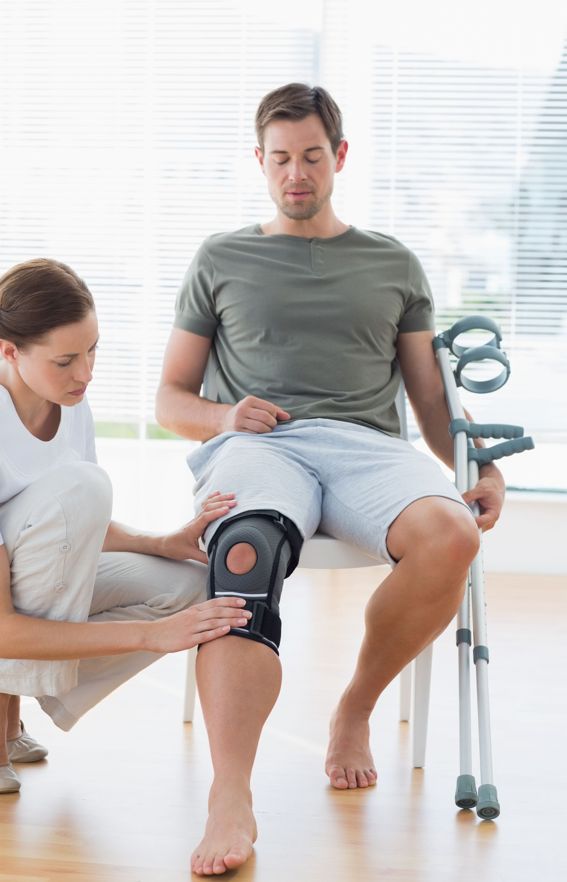 A woman is helping a man with a knee brace.