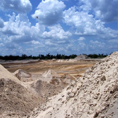 Sandy terrain under a cloudy blue sky, likely a quarry or construction site.