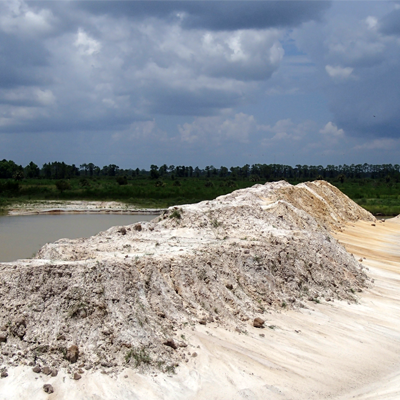 A white sandy landscape with a body of water, under a cloudy sky.