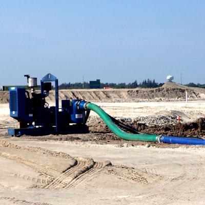 Blue water pump pumping water out of a construction site, with a green hose and blue pipe.