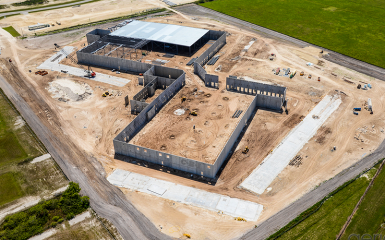 Aerial view of a concrete building under construction with walls and a partially completed roof.