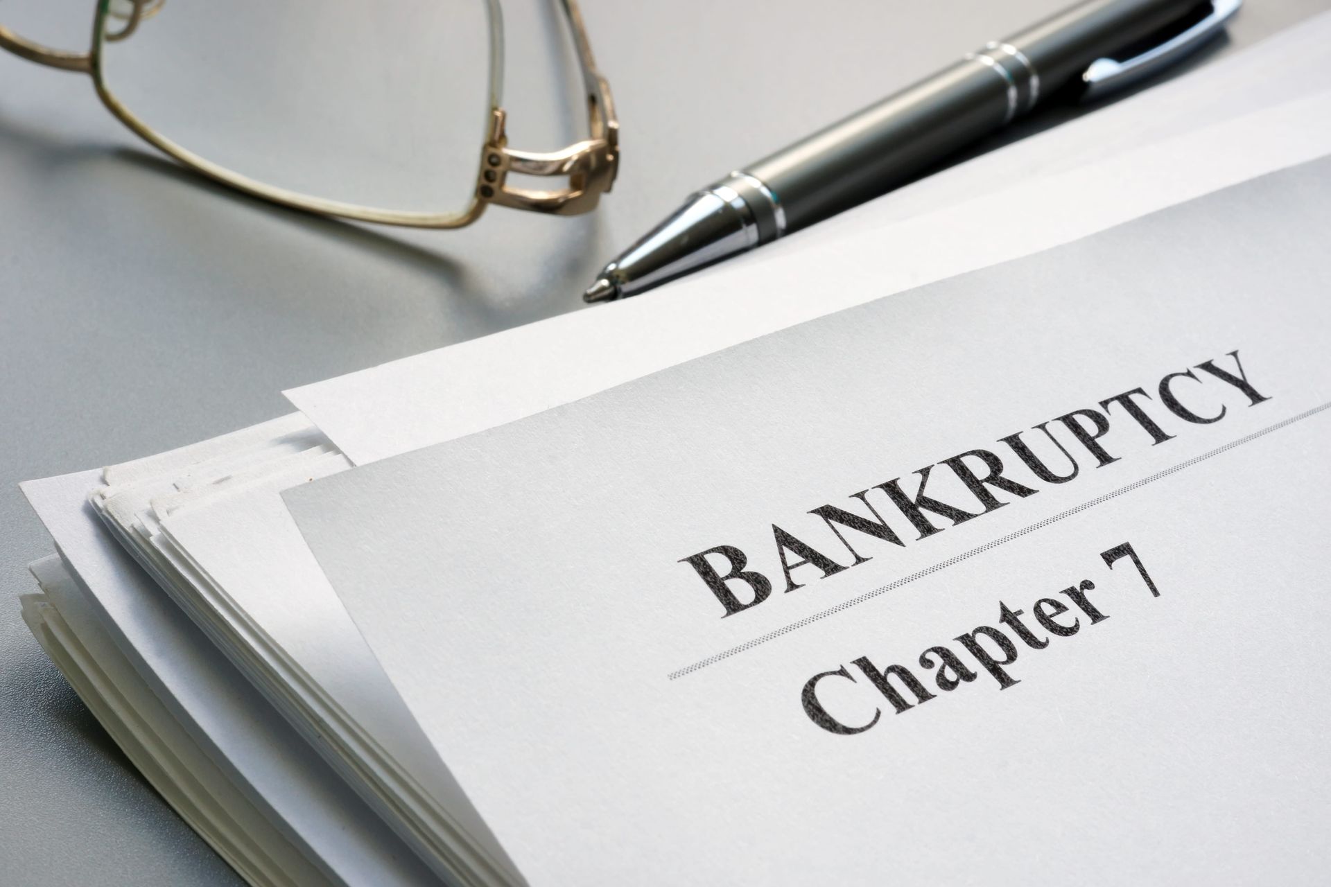 Paper and glasses on a table, paper says chapter 7 bankruptcy