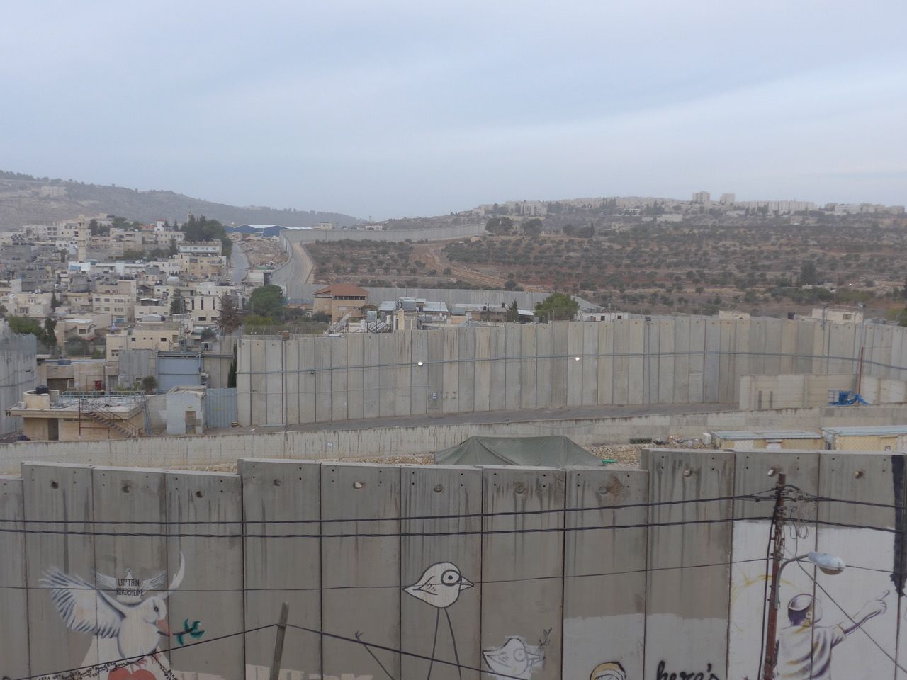 Convoluted path of the barrier, here obstructing access to the trees to the right of the barrier
A Settlement on a hill in background