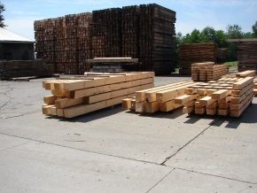 A lot of wooden beams are stacked on top of each other in a yard.