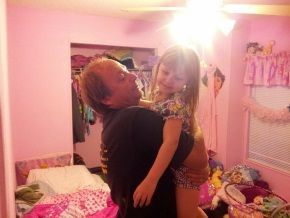 A man is holding a little girl in his arms in a pink room.