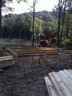 A man is working on a wooden deck in the woods.