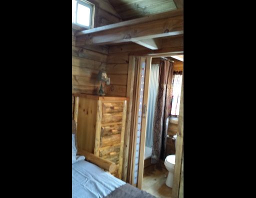 A bedroom with a bed , dresser , toilet and shower.