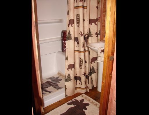 A bathroom with a moose rug and shower curtain
